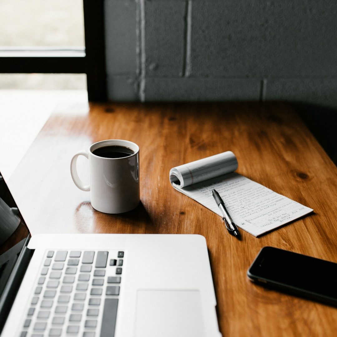 Bild Schreibtisch Schreibtisch mit Laptop, Kaffeetasse, Notizblock und Smartphone.