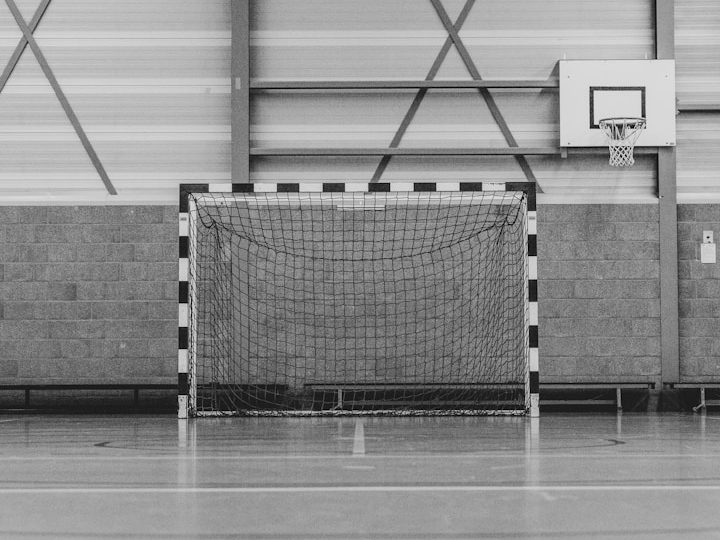 Handballtor in einer Sporthalle, hinten mit Markierungen auf dem Boden.