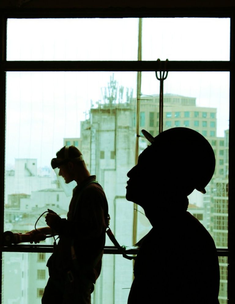 Silhouetten von Arbeitern in einem Hochhaus mit Bauarbeiten im Hintergrund.