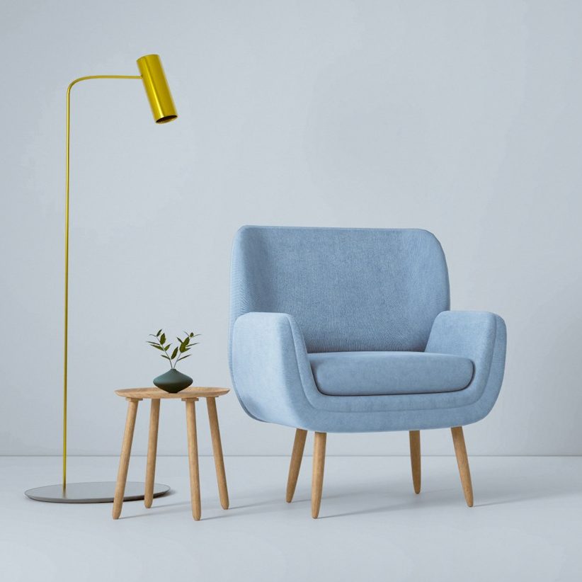 Bild unabhängig Blaues Sofa mit Holzbeinen, daneben eine Stehlampe und zwei kleine Beistelltische.